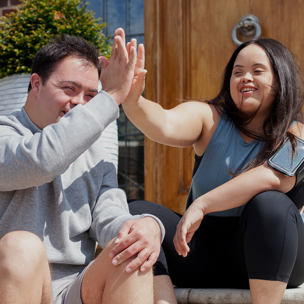 Two seated young people touching hands together in a high-five