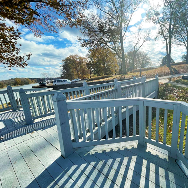 A wooden ramp leading to a deck in a park near a body of water