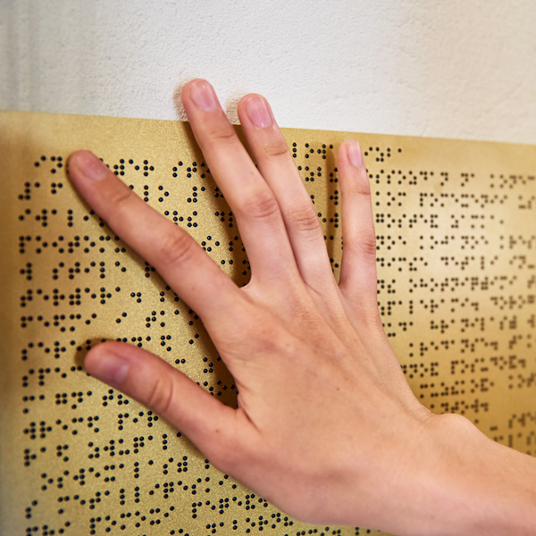 Close-up view of a hand feeling a sign written in Braille